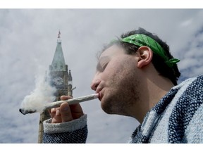 A man smokes a joint at the Fill the Hill marijuana rally on Parliament Hill in Ottawa on Sunday, April 20, 2014.