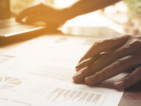 Young businessman holding pen on charts and graph