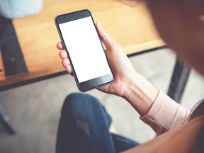 Woman using smart phone in cafe. hand holding smart phone white screen (Getty Images)