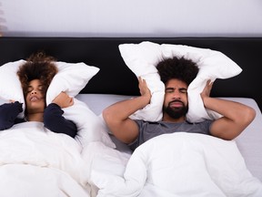 Young Couple Covering Their Ears With Pillow