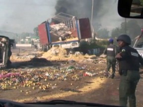 Destroyed vehicles and debris is strewn across the road as police attempt to restore calm, in the town of Jos, Nigeria, Sunday June 25, 2018.