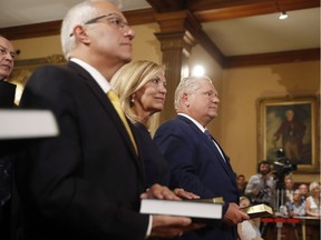 Doug Ford, right, is sworn in as premier of Ontario during a ceremony at Queen's Park in Toronto on Friday, June 29, 2018. Cabinet ministers Christine Elliott and Vic Fedeli look on.