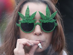 This file photo taken on April 20, 2017 shows a woman smoking marijuana on Parliament Hill waiting for the clock to hit 4:20 p.m. on 4/20 in Ottawa.