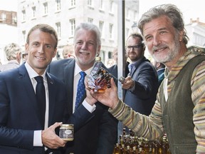 French President Emmanuel Macron, left, and Quebec Premier Philippe Couillard, centre, are seen at a maple syrup stand during a visit to Old Montreal on Thursday, June 7, 2018.