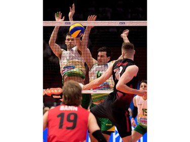 After Australia's Beau Graham, left, and Paul Sanderson block the ball, Canadian Bradley Robert Gunter tries to reach back to tip it back into play. Wayne Cuddington/Postmedia