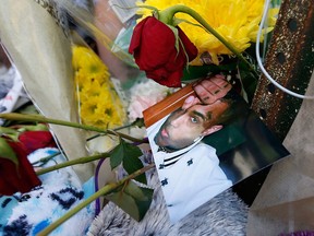 A photo of rap singer XXXTentacion lies amongst flowers and stuffed animals left at a memorial, Tuesday, June 19, 2018, outside Riva Motorsports in Deerfield Beach, Fla., where the troubled rapper was killed the day before.