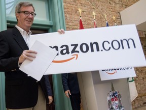 Mayor Jim Watson removes a sign after officially announcing that Amazon will be building a large fulfillment centre in the east end of the city.