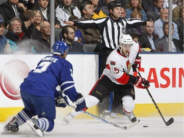 TORONTO - OCTOBER 6:  Erik Karlsson #65 of the Ottawa Senators carries the puck as he is defended by Ian White #7 of the Toronto Maple Leafs during their NHL game at the Air Canada Centre October 6, 2009 in Toronto, Ontario.