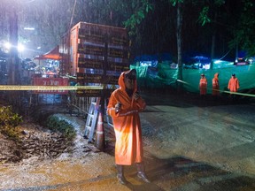 A Thai police officer guards an area under rainfall near the Tham Luang cave at the Khun Nam Nang Non Forest Park in Mae Sai district of Chiang Rai province on Saturday as rescue operation continues for the 12 boys and their soccer team coach.