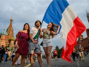 French fans hold their country's flag as they pose for a photo at Red Square in Moscow on Saturday, the eve of the World Cup final between France and Croatia.