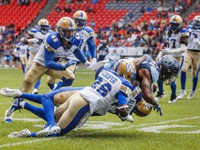 Toronto Argonauts' James Wilder Jr. is tackled by Winnipeg Blue Bombers' Tyneil Cooper (centre) and teammates Brandon Alexander and Jovan Santos-Knox during first-half CFL action in Toronto on Saturday, July 21, 2018. (MARK BLINCH/THE CANADIAN PRESS)