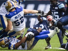 Argonauts kick returner Martese Jackson, right, fumbles the ball as he's being tackled by Blue Bombers players during the first half of Saturday's game in Toronto.