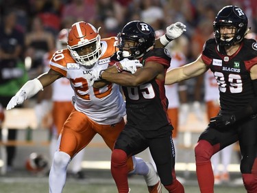 The Lions' Bo Lokombo (20) tries to strip the ball from Redblacks kick returner Diontae Spencer (85) during the first half.