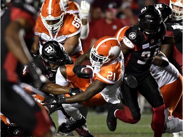 Lions tailback Brandon Rutley (21) is tackled by Redblacks linebacker Avery Williams (42).