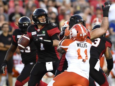 Redblacks quarterback Trevor Harris looks for a receiver down the field as Lions defensive end Odell Willis (11) tries to apply a pass rush on a first-half play.