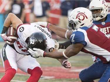 Redblacks receiver Brad Sinopoli, left, is dragged down by Alouettes defensive lineman John Bowman.