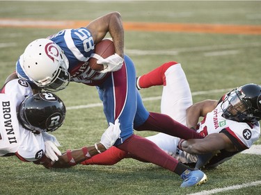 Redblacks linebacker Kevin Brown II, left, and Corey Tindal bring down Alouettes receiver B.J. Cunningham (85) during the first half.