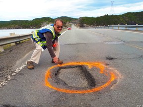 Ernest Barnes, Summerford's "Pothole Man," has made it his mission to mark the dangerous stretches of road along the Road to the Isles." Barnes is seen in an undated handout image circling a pothole along a stretch of road. (The Canadian Press/HO-David Boyd)