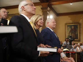 Doug Ford (right) is sworn in as premier of Ontario during a ceremony at Queen's Park in Toronto on Friday, June 29, 2018. Cabinet ministers Christine Elliott and Vic Fedeli look on.
