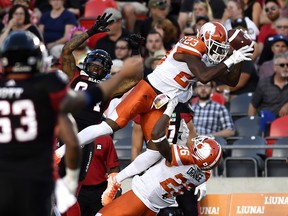 BC Lions’ Anthony Thompson (23) falls over teammate Anthony Orange (26) as he attempts to make an interception against Redblacks’ R.J. Harris (84) during first-half action in Ottawa on Friday night. )Justin Tang/The Canadian Press)