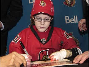 Jonathan Pitre intently signs a one-day contract to be a Senators scout in November 2014. A passionate Senators fan, Pitre died in April.  Tony Caldwell/Postmedia