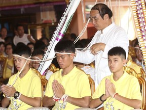 Soccer coach Ekkapol Janthawong, center, and members of the rescued soccer team attend a Buddhist ceremony that is believed to extend the lives of its attendees as well as ridding them of dangers and misfortunes in Mae Sai district, Chiang Rai province, northern Thailand, Thursday, July 19, 2018. (AP Photo/Sakchai Lalit)