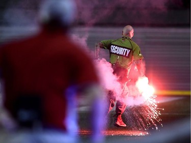 A security guard runs while holding a flare that was thrown onto the field during second half Canadian Championship soccer action between the Ottawa Fury FC and the Toronto FC, in Ottawa on Wednesday, July 18, 2018.