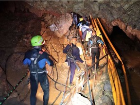 In this photo released by Royal Thai Navy on Saturday, Thai rescue team members walk inside a cave where 12 boys and their soccer coach have been trapped since June 23.