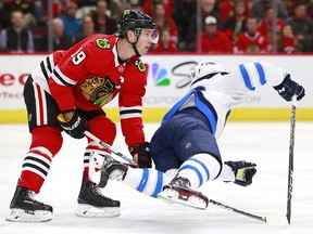 Chicago Blackhawks centre Jonathan Toews (19) trips Winnipeg Jets center Marko Dano Friday, Jan. 12, 2018, in Chicago. (AP Photo/Jeff Haynes)