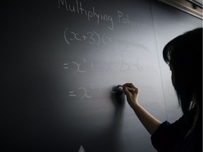 A professor writes on a chalkboard.