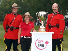 Brooke Henderson poses with two RCMP officers and the champion's trophy after winning the CP Women's Open at Regina on Sunday.