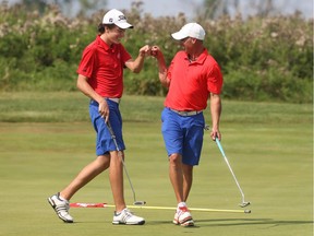 Allen McGee, right, fist-bumps his son Hunter after sinking a birdie putt on the 15th hole of Friday's round. Jean Levac/Postmedia
