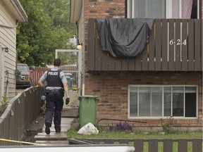 An RCMP member enters a house in Cochrane, Alta., while executing a search warrant on Saturday. The property is believed to be connected to a person Mounties detained Friday after a tourist was shot while driving near Morley, Alta.