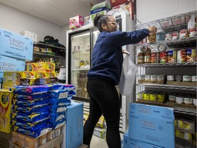 Community and Family Services Supervisor Diana Javiers fills a food bag in the cramped food storage room at The Salvation Army Ottawa Booth Centre. Errol McGihon/Postmedia