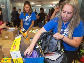 Volunteers Cara Deszcz, right, helps pack backpacks for the Caring and Sharing Exchange.