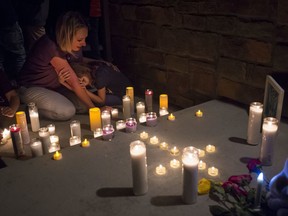 Jeanna Dietz hugs her daughter Eva, 7, while looking onto a memorial on the front porch while others gather for a candlelit vigil for Shanann Watts and her two daughters, Bella, 4, and Celeste, 3, in front of the Watts' home on Friday, Aug. 17, 2018, in Frederick, Colo.