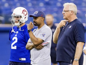 Alouettes QB Johnny Manziel, left, stands beside offensive co-ordinator Khari Jones and head coach Mike Sherman, right, during a practice at Olympic Stadium in late July.