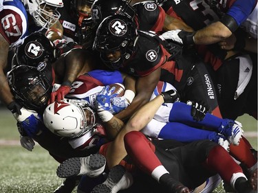 Alouettes running back Tyrell Sutton (20) is wrapped up by Redblacks defenders during second-half action at TD Place stadium.