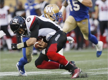 Redblacks quarterback Trevor Harris fumbles the ball after getting hit by Blue Bombers defensive back Kevin Fogg (3) during the first half.