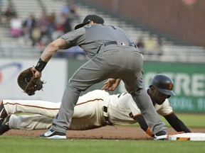 San Francisco Giants' Andrew McCutchen dives safely back to first base on a pick-off attempt as Arizona Diamondbacks first baseman Paul Goldschmidt waits for the throw in the first inning of a baseball game, Tuesday, Aug. 28, 2018, in San Francisco.