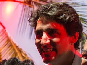 Prime Minister Justin Trudeau is illuminated by a red spotlight as he poses for a photograph with Richmond Night Market staff during a visit to the market in Richmond, B.C., on Saturday Aug. 4, 2018.