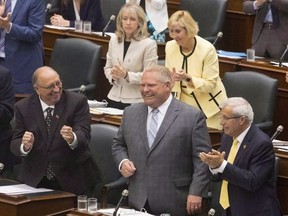 Ontario Premier Doug Ford is applauded by his PC Party members during Question Period at the Ontario Legislature in Toronto on July 30, 2018. The Ontario government passed a controversial bill to reduce the size of Toronto city council on Tuesday, capping off a rare and tumultuous summer legislative sitting that saw the newly elected Progressive Conservatives forge ahead on several key campaign promises. The legislation, one of two passed during the month-long sitting, was announced unexpectedly in late July, putting the province at loggerheads with the city as they prepare for a fall municipal election and prompting critics to accuse the new government of circumventing the democratic process.