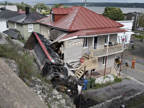A dump truck lies on its side after crashing into a house, Thursday, August 2, 2018 in Chateau-Richer Que.