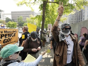 A protester holds up a peace sign while marching on the side of the street of anti-fascist groups counter-protesting as members of Patriot Prayer and other groups supporting gun rights demonstrate across the street during a rally, Saturday, Aug. 18, 2018, at City Hall in Seattle.