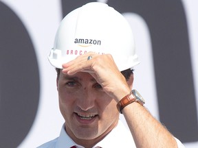 Prime Minister Justin Trudeau adjusts his hat as he participates in a ground breaking ceremony for an Amazon distribution centre in Ottawa, Monday Aug. 20, 2018.