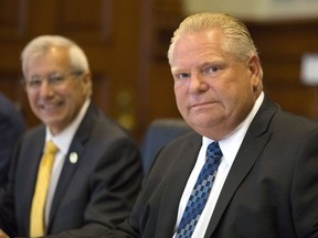 Ontario Premier Doug Ford, right, sits with Provincial Finance Minister Vic Fedeli and members of cabinet, as they meet with economists from major Canadian banks to discuss the province's economic outlook and the ongoing NAFTA negotiations at Queens Park Legislature, in Toronto on Thursday, August 30, 2018.