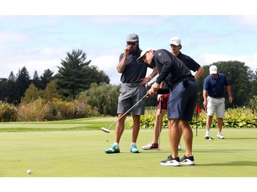 Chris Wideman (M), Erik Karlsson (L) and Thomas Chabot of the Ottawa Senators warm up on the putting green.