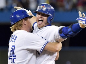Toronto Blue Jays third baseman Josh Donaldson, right reacts with first base coach Tim Leiper, left, after hitting a RBI single to defeat the Kansas City Royals during 11th inning AL baseball action in Toronto on Friday, July 31, 2015. (THE CANADIAN PRESS/Nathan Denette)