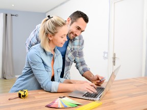 cheerful young couple renovating home design and choosing colors paint and furnitures on internet with a laptop computer