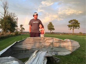 Andrew Mactaggart and daughter Kirsten, 8, with a large piece of metal deposited on his front lawn. He believes it came from a neighbour's barn.